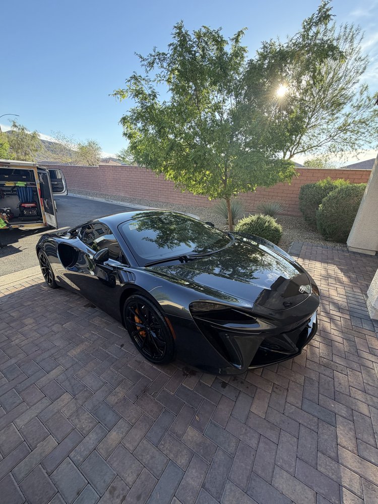 Freshly detailed black McLaren parked in a driveway after mobile detailing service